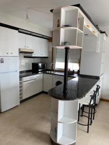 een keuken met een zwarte tafel en witte kasten bij precioso apartamento con vistas al mar in Sanxenxo