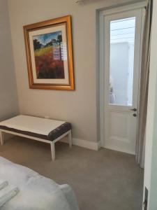 a bedroom with a bench and a painting and a window at Margie's Place in Swellendam