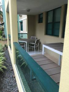 uma varanda com uma mesa, uma mesa e cadeiras em AQUATIKA BEACH APT 1ST FL em Loiza
