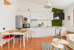 a kitchen with white cabinets and a table and chairs at Fast wifi & Relax bungalow Ipanema Gran Canaria in Maspalomas
