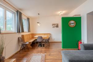salon z zieloną ścianą, stołami i krzesłami w obiekcie Anblick Appartement with lake view w mieście Zell am See