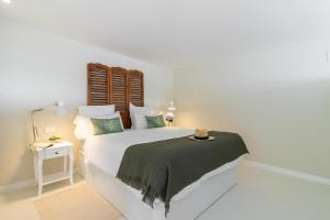 ein weißes Schlafzimmer mit einem großen weißen Bett mit grünen Kissen in der Unterkunft Santa Brigida Window Suite in Santa Brígida