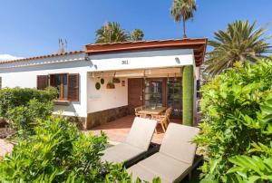 ein Haus mit einer Terrasse mit Stühlen und einem Tisch in der Unterkunft Fast wifi & Relax bungalow Ipanema Gran Canaria in Maspalomas