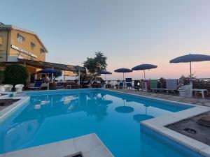 a swimming pool with blue water and umbrellas at Hotel Piccolo Mondo in Acquappesa