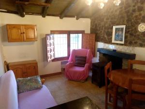 ein Wohnzimmer mit einem rosa Stuhl und einem Tisch in der Unterkunft Casitas La Purísima Macho in Requena