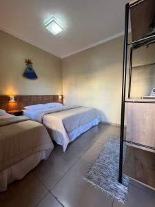 a hotel room with two beds and a mirror at Rogai Hotel Pousada in Aparecida