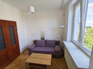 een woonkamer met een paarse bank en een tafel bij Comfortable and quiet flat in Central Warsaw in Warschau