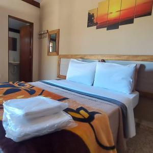 a bedroom with a large bed with white pillows at Pousada Portal da Serra - Chalés in Carrancas