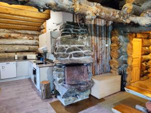 a kitchen with a stone fireplace in a log cabin at Villa Suopursu in Karesuvanto