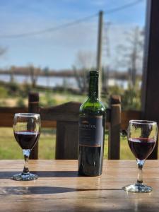 dwa kieliszki czerwonego wina siedzące na drewnianym stole w obiekcie CARELHUE GUAZU w mieście Villa Paranacito