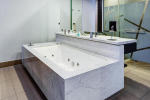una grande vasca bianca in un bagno con specchio di Wyndham Santiago Pettra a Santiago