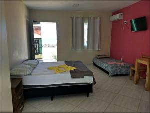 a bedroom with two beds and a red wall at pousada costa do meio in Saquarema