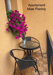 a table and a chair on a balcony with flowers at Małe Pieniny in Szczawnica