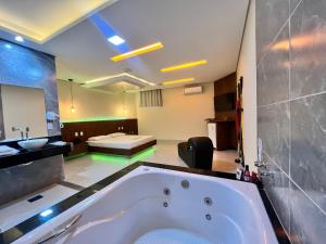 a large bathroom with a tub and a bedroom at Bliss Motel in Brasilia