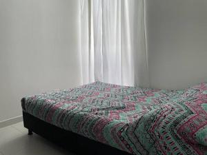 una cama con un edredón junto a una ventana en Confortable Apartamento en Ibagué con piscina solo Fines de semana solo para FAMILIAS, en Ibagué