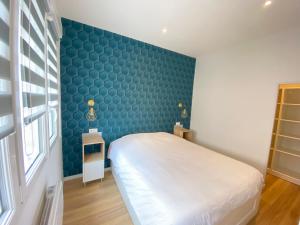 - une chambre avec un lit blanc et un mur bleu dans l'établissement Le Sacré - CENTRE - Cour privative - PARKING, à Reims