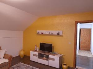 un salon avec une télévision sur un mur jaune dans l'établissement Pejovic, à Višegrad