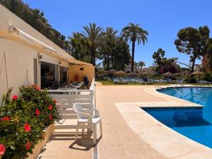 um resort com piscina, cadeiras e palmeiras em Vistas al Mar Marbella del Este em Marbella