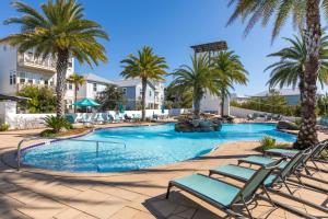 una piscina con palmeras y tumbonas en Seabreeze 30A, en Blue Mountain Beach