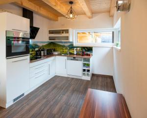 a kitchen with white cabinets and a wooden floor at Chalets Lunz am See in Lunz am See