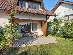 eine Terrasse eines Hauses mit einem Tisch und Rosen in der Unterkunft Ferienwohnung Riposo in Meersburg