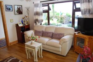 a living room with a white couch and a tv at The Ocean Wave Bed & Breakfast in Cleggan