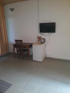um quarto com uma mesa, uma televisão e uma cadeira em Abuesi Beach Resort em Takoradi