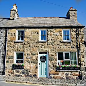 an old stone house with a blue door and windows at Porthyraur castle view, beach, parking,EV point Pet friendly in Criccieth