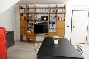 un soggiorno con tavolo, TV e scaffali di Villa Green a Pianezza