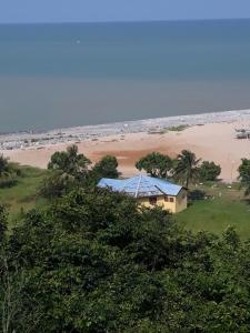 uma casa com um telhado azul ao lado de uma praia em Abuesi Beach Resort em Takoradi