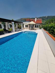 a swimming pool with blue water in front of a house at Villa Maslina in Ljubuški