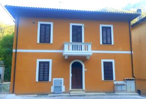 uma casa laranja com uma varanda branca e uma porta em Luce Marmore em Le Marmore