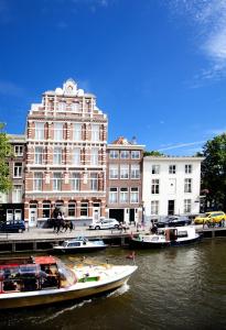 boats are docked in the water near a large building at Hotel Nes in Amsterdam