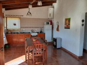 eine Küche mit einem Tisch und Stühlen sowie einem Kühlschrank in der Unterkunft Cabañas Loma de El Pelao in Tafí del Valle