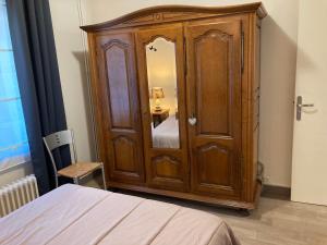 einen Holzschrank mit einem Spiegel im Schlafzimmer in der Unterkunft 13 boulvard Solférino T2 agréable pour deux pers in Poitiers