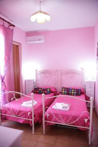 Duas camas num quarto com paredes cor-de-rosa em B&B Gi & Giò em Càbras