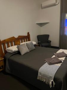 a bedroom with two beds and a chair at Oriental Hotel Tumut in Tumut