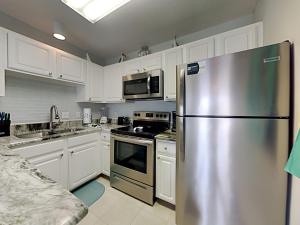 a kitchen with a stainless steel refrigerator and white cabinets at Grand Caribbean #306 West in Perdido Key