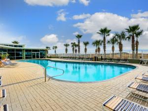 a large swimming pool with palm trees and a building at Tidewater Orange Beach #209 in Orange Beach