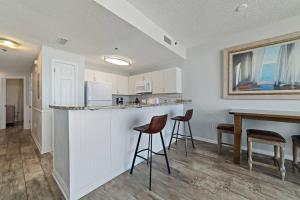 a kitchen with a bar with stools and a table at Beach Club C-509 in Gulf Shores
