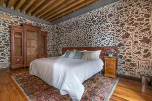 Un dormitorio con una cama y una pared de piedra. en Historic Suite w balconies to Cathedral & Rooftop CASA SAUTO 5, en Ciudad de México