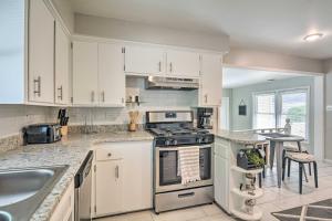 La cuisine est équipée de placards blancs et d'un four avec plaques de cuisson. dans l'établissement Charming Springfield Home with Private Backyard, à Springfield