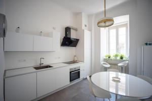 eine weiße Küche mit einem Tisch und einem weißen Kühlschrank in der Unterkunft Art & History - NEW - Modern Classic Apartment in Triest