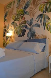 1 dormitorio con 1 cama con un mural de plantas en Raggio di Sole, en Gaeta