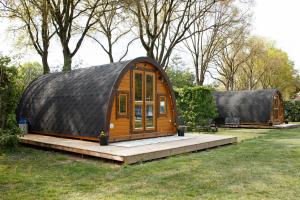 a small house with a black roof in a field at Costa Kabrita in Huijbergen