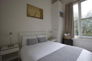 1 dormitorio con 1 cama blanca y 2 ventanas en Large 2 Beds Flat Overlooking Clapham Common Park, en Londres