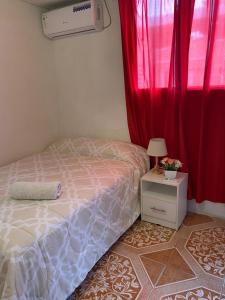 a bedroom with a bed and a window with red curtains at Los Tamarindos Posadamanabita in Portoviejo