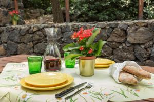 a table with yellow plates and a vase with flowers at Le Querce Dell'Etna B&B in Ragalna