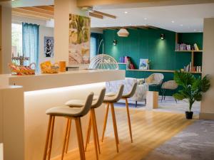 a kitchen with green walls and a counter with stools at Best Western Le Bois de la Marche in Poitiers
