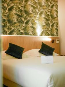 a bedroom with a bed with two black pillows at Best Western Le Bois de la Marche in Poitiers